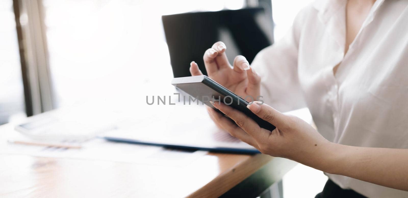 Close up hand of woman using smartphone at office. by wichayada