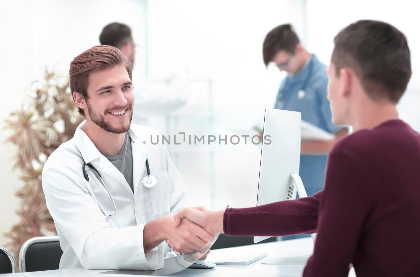 handshake between doctor and patient sitting at Desk