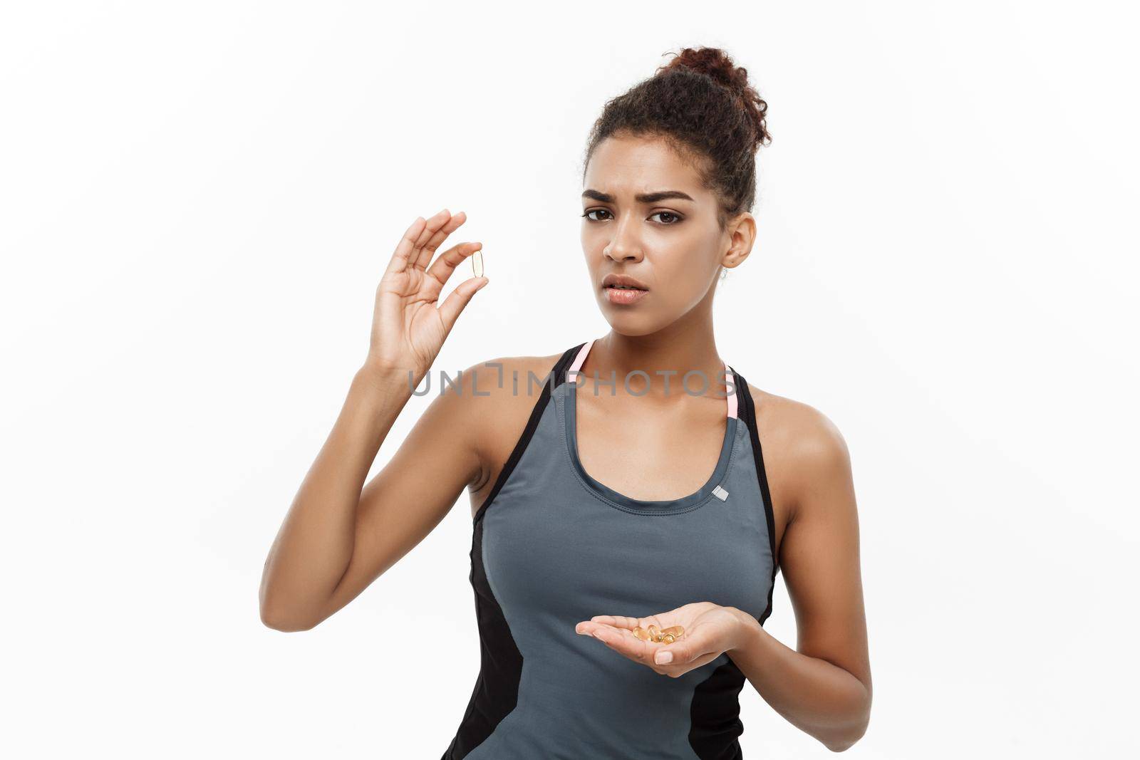 healthcare concept - Closeup portrait of beautiful African American taking a pill of Cod liver oil. Isolated on white studio background.