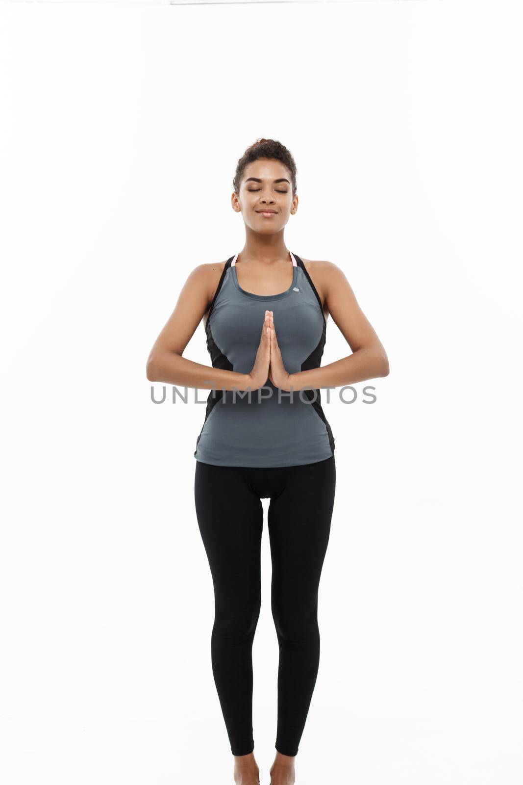 Healthy and Fitness concept - Beautiful American African lady in fitness clothing doing yoga and meditation. Isolated on white background. by Benzoix