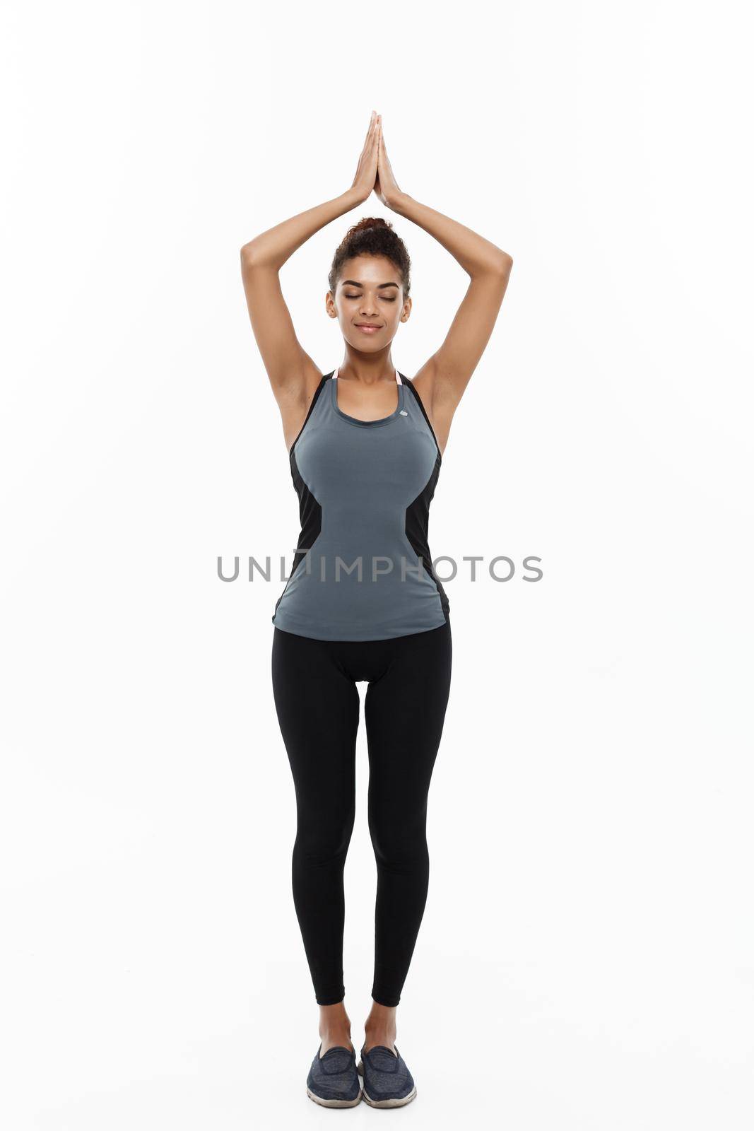 Healthy and Fitness concept - Beautiful American African lady in fitness clothing doing yoga and meditation. Isolated on white background