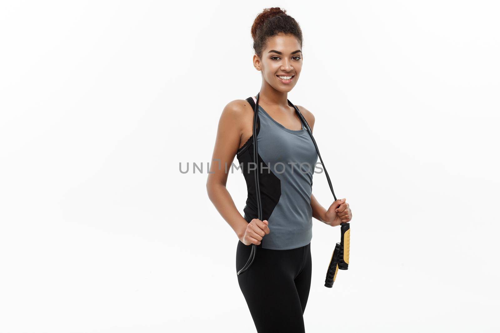 Sport, training, lifestyle and Fitness concept - portrait of beautiful happy African American woman exercising with jumping rope. Isolated on white studio background. by Benzoix