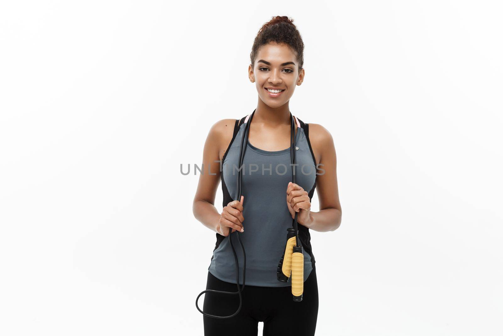 Sport, training, lifestyle and Fitness concept - portrait of beautiful happy African American woman exercising with jumping rope. Isolated on white studio background. by Benzoix