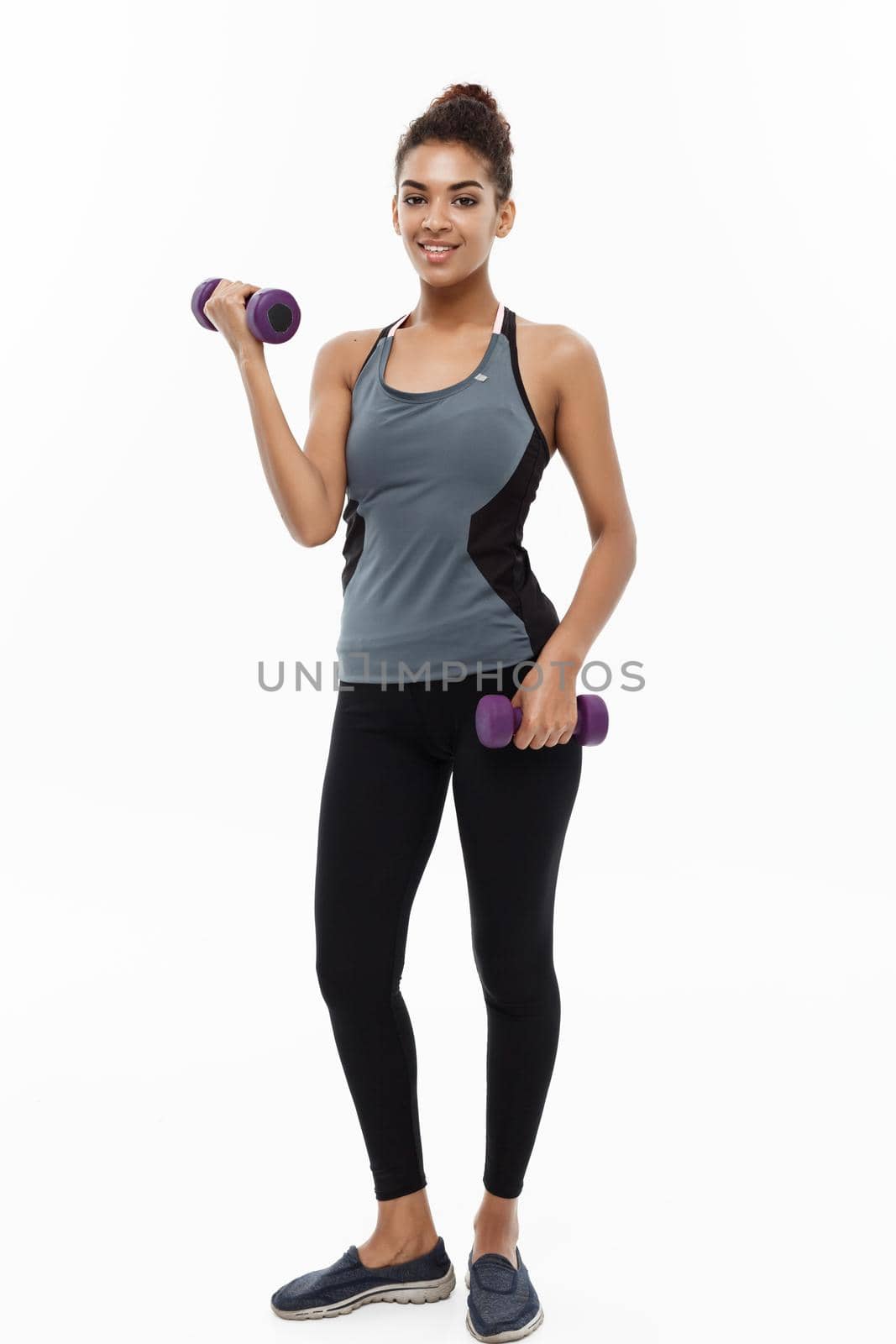 Healthy and Fitness concept - Full-length of portrait Beautiful American African lady in grey fitness clothes workout with dumbbell. Isolated on white background. by Benzoix