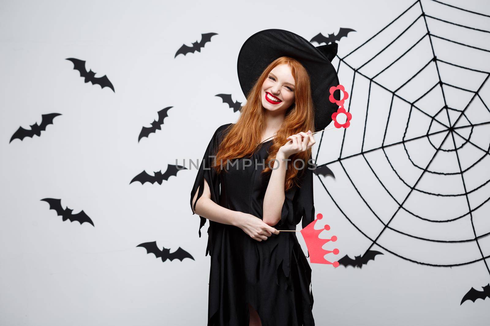 Halloween concept - Beautiful girls in black witch dresses holding party props. by Benzoix