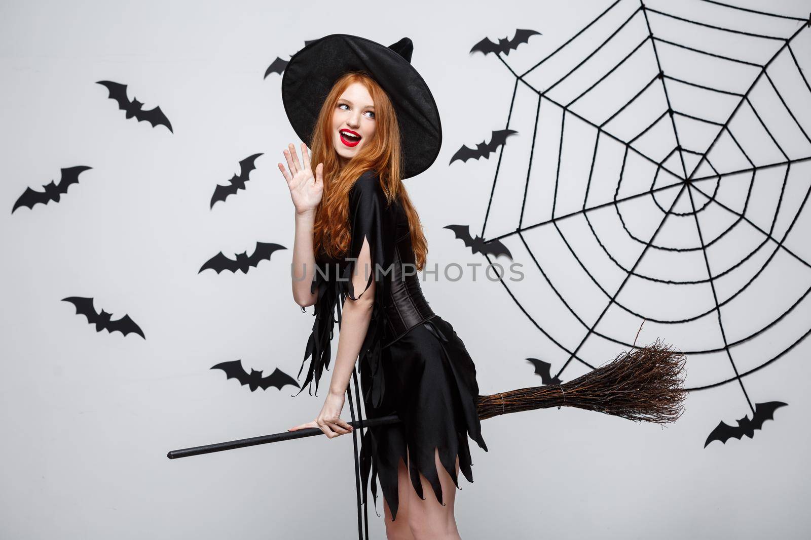 Halloween Concept - Happy elegant witch enjoy playing with broomstick halloween party over grey background