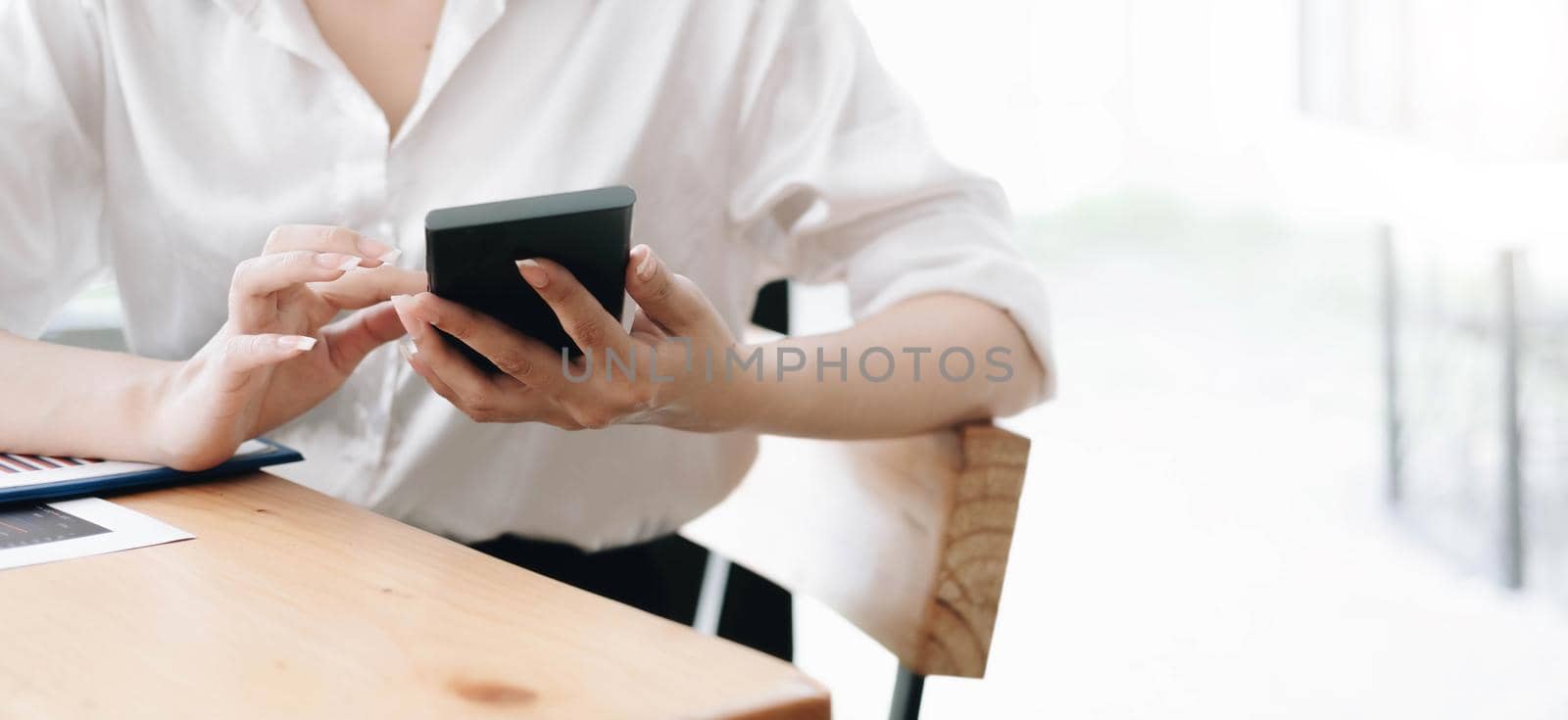 Close up hand of woman using smartphone at office.