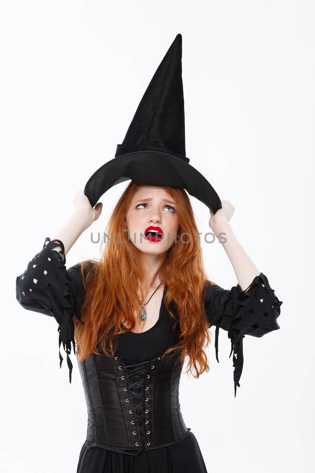 Halloween witch concept - Happy Halloween Sexy ginger hair Witch fighting with her magic hat flying over her head. Isolated on white background