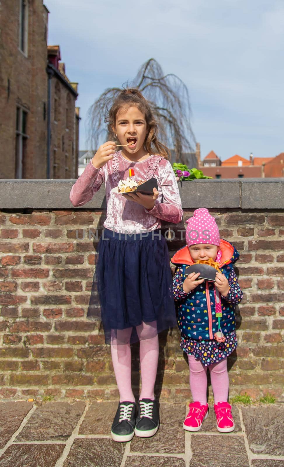 Belgian waffles are eaten by children on the street. Selective focus. by yanadjana