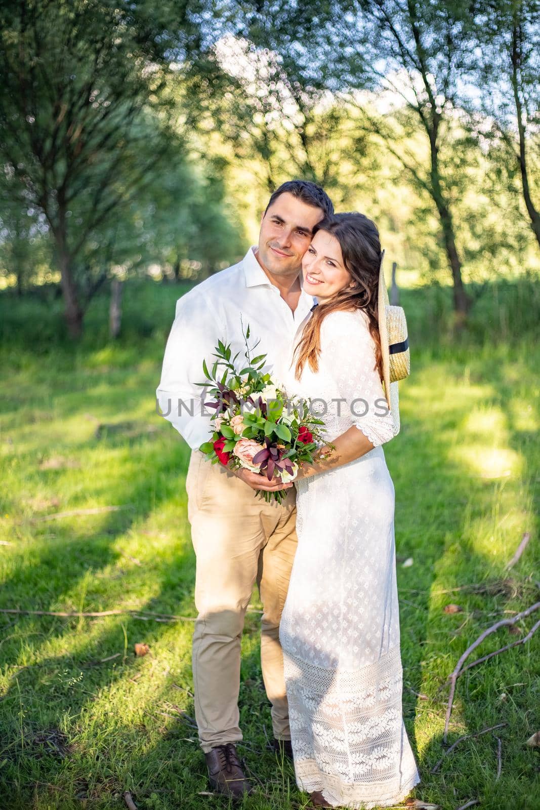 beautiful newlyweds stand on a green meadow hugging each other, rustic style wedding by Anyatachka