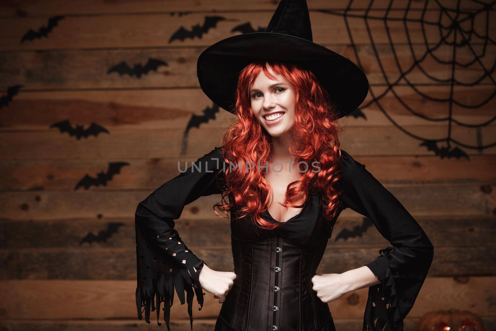 Halloween witch concept - Happy Halloween red hair Witch holding posing over old wooden studio background