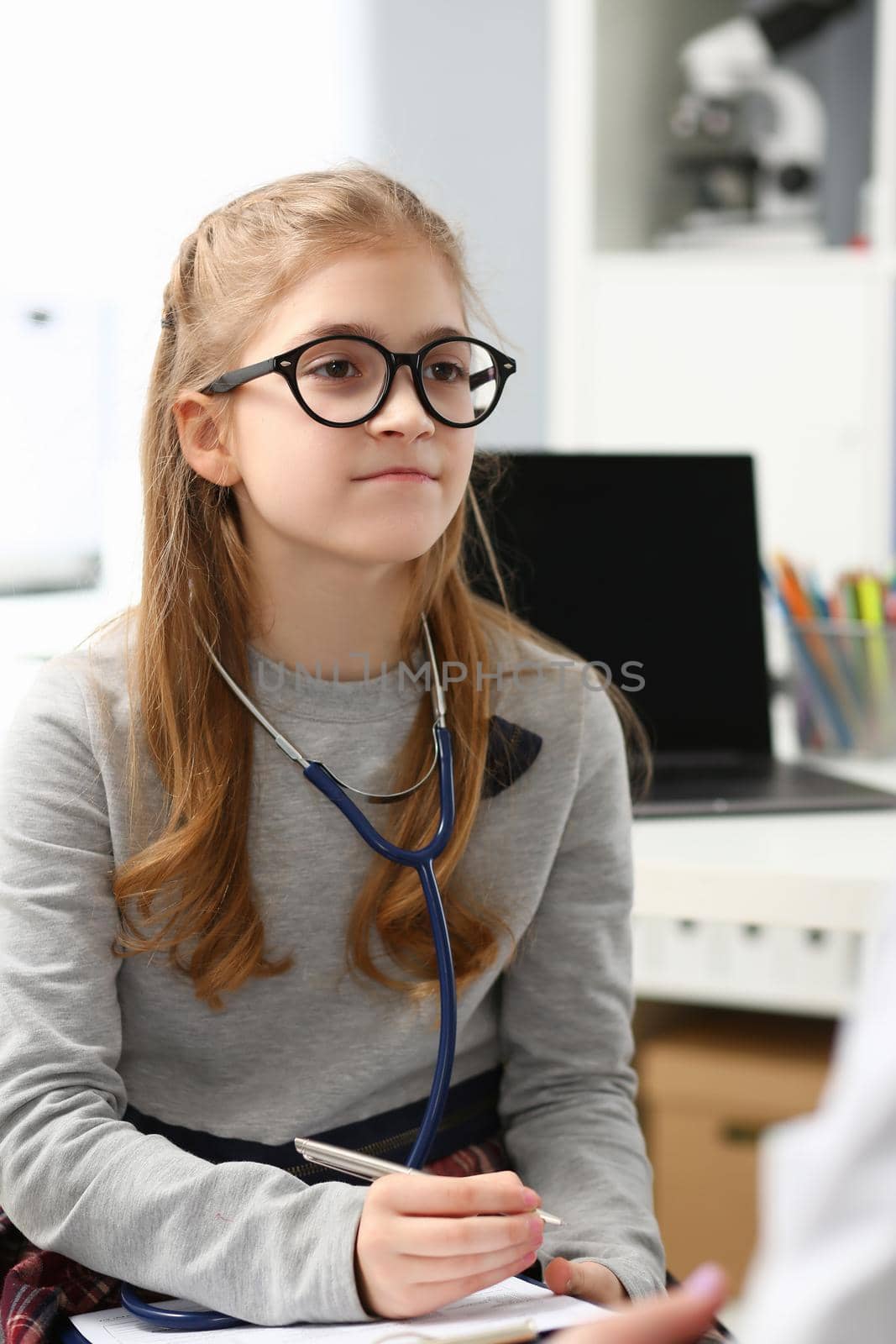 Young child wants to be doctor, write advices on paper, wear stethoscope equipment on neck by kuprevich