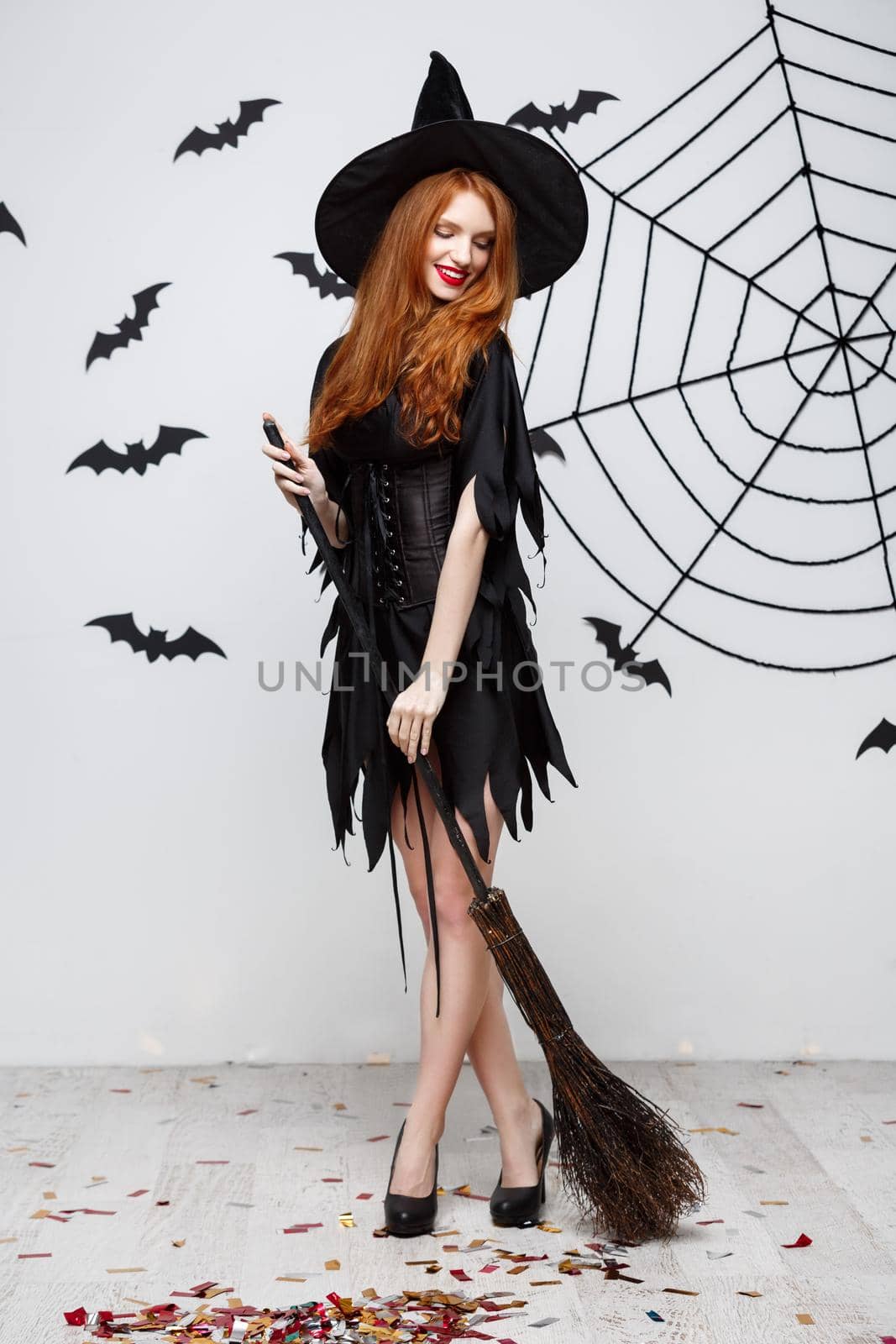 Halloween Concept - Happy elegant witch enjoy playing with broomstick halloween party over grey background. by Benzoix