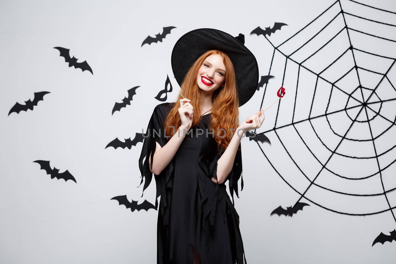 Halloween concept - Beautiful girls in black witch dresses holding party props