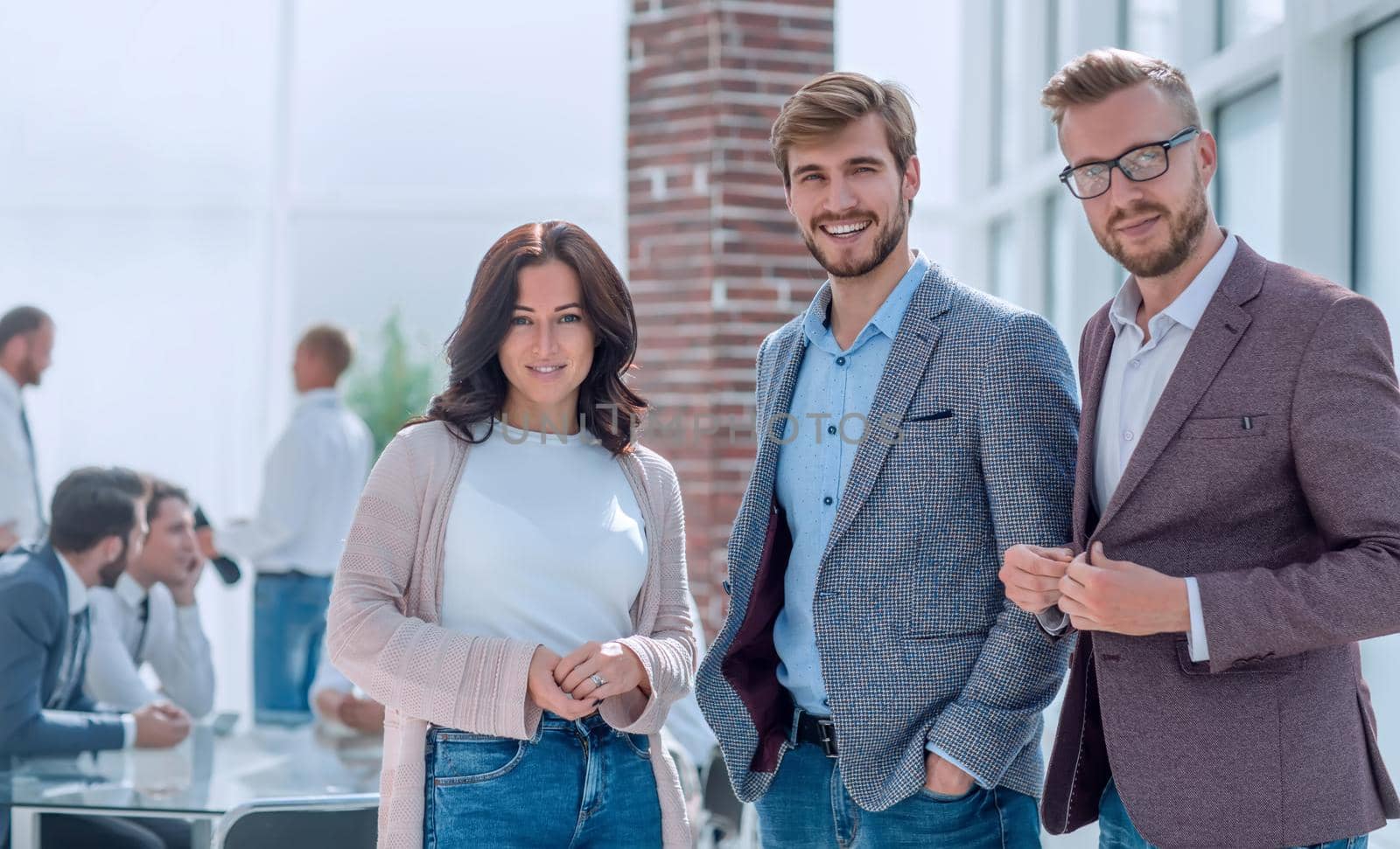 three young employees standing in a modern office by asdf