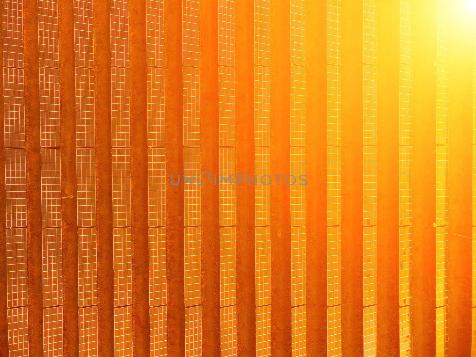 Aerial top view of a solar panels power plant. Photovoltaic solar panels at sunrise and sunset in countryside from above. Modern technology, climate care, earth saving, renewable energy concept