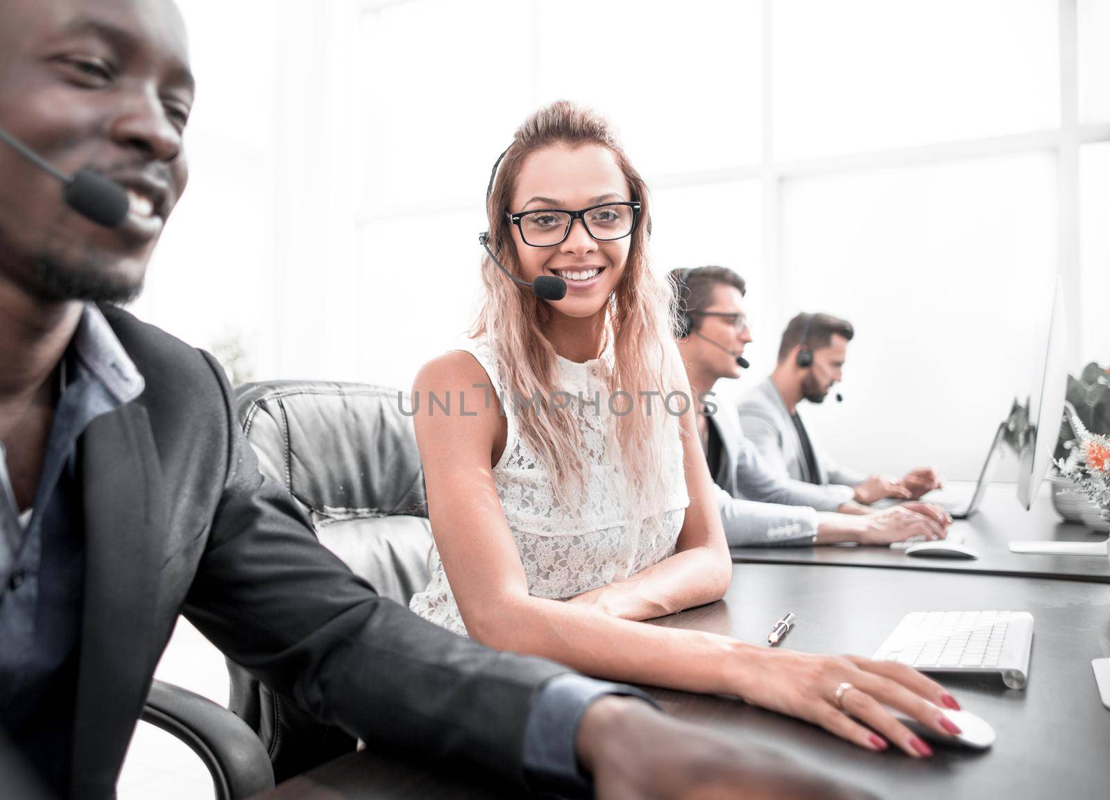 young business woman sitting at table in call center by asdf