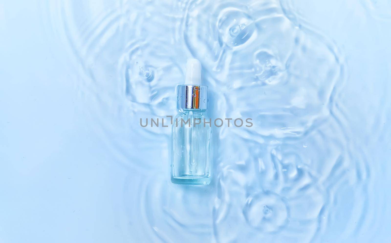 Cosmetics in a bottle in water, skin hydration concept. Hyaluronic acid. Selective focus. Nature.