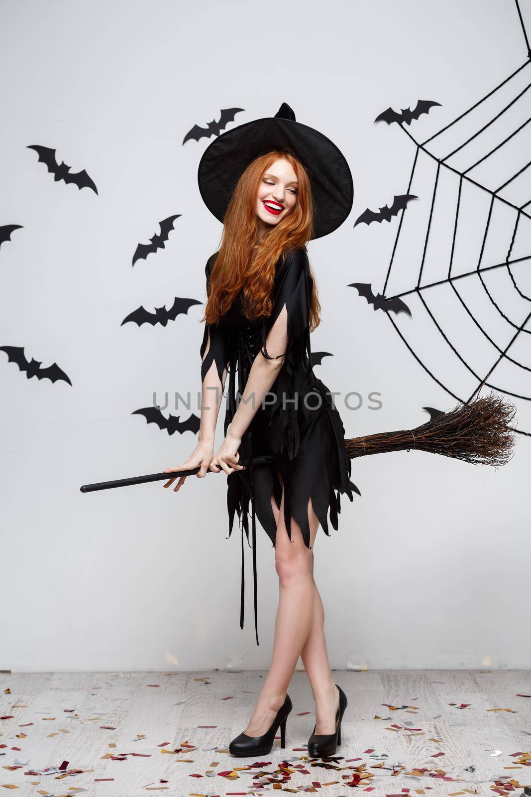 Halloween Concept - Happy elegant witch enjoy playing with broomstick halloween party over grey background. by Benzoix