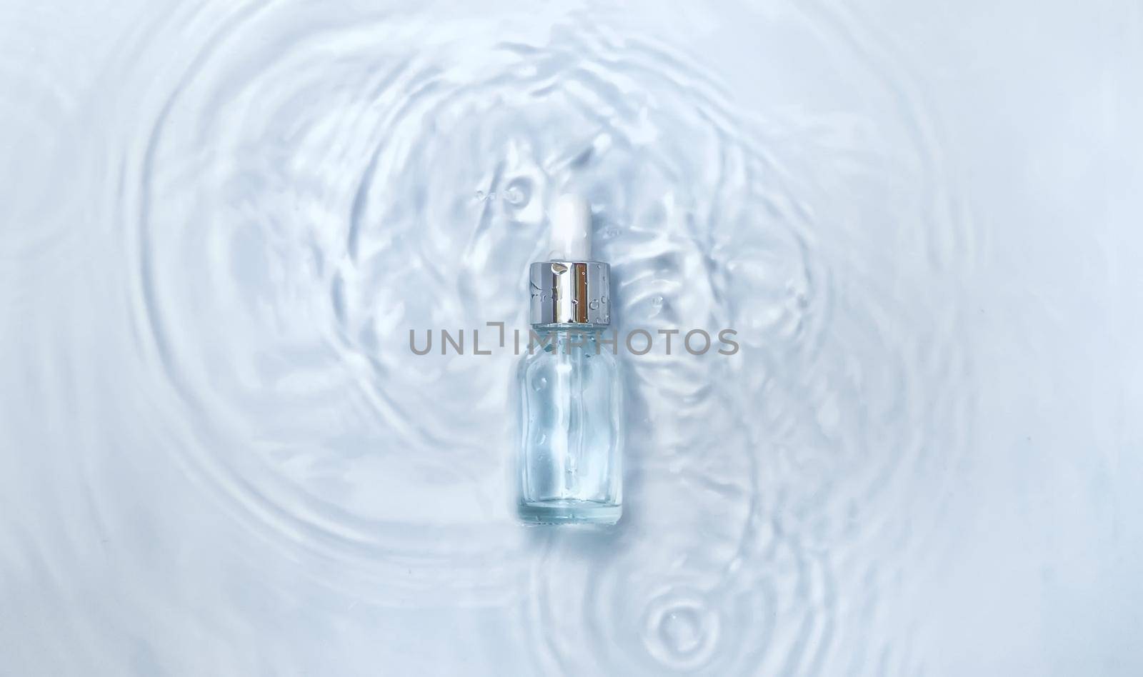 Cosmetics in a bottle in water, skin hydration concept. Hyaluronic acid. Selective focus. Nature.