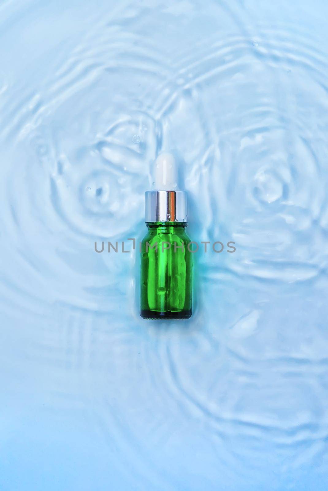 Cosmetics in a bottle in water, skin hydration concept. Hyaluronic acid. Selective focus. Nature.