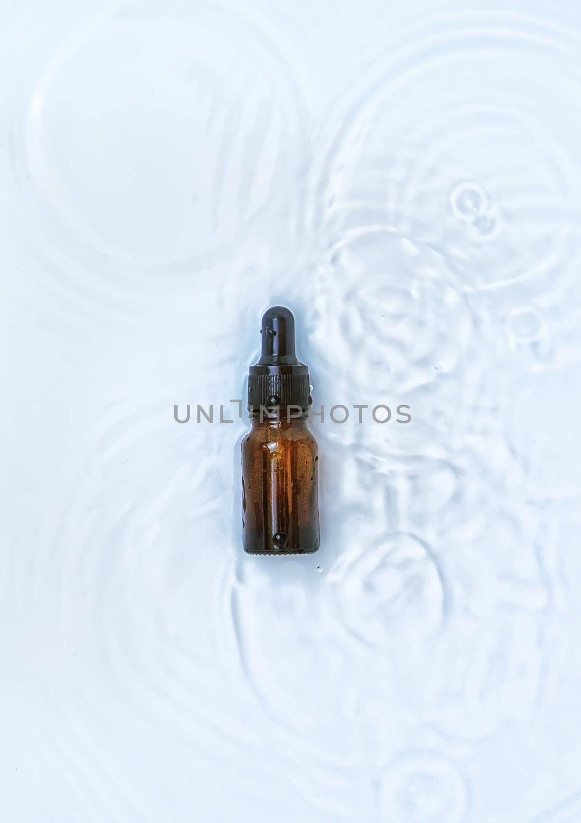 Cosmetics in a bottle in water, skin hydration concept. Hyaluronic acid. Selective focus. Nature.
