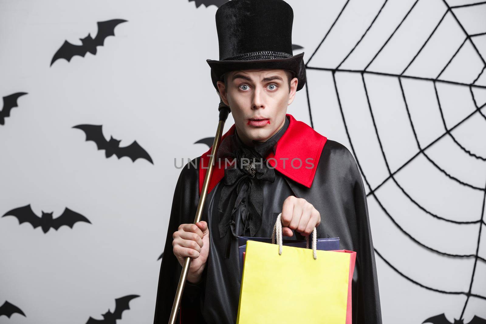 Vampire Halloween Concept - Happy handsome caucasian Vampire holding colorful shopping bag. by Benzoix