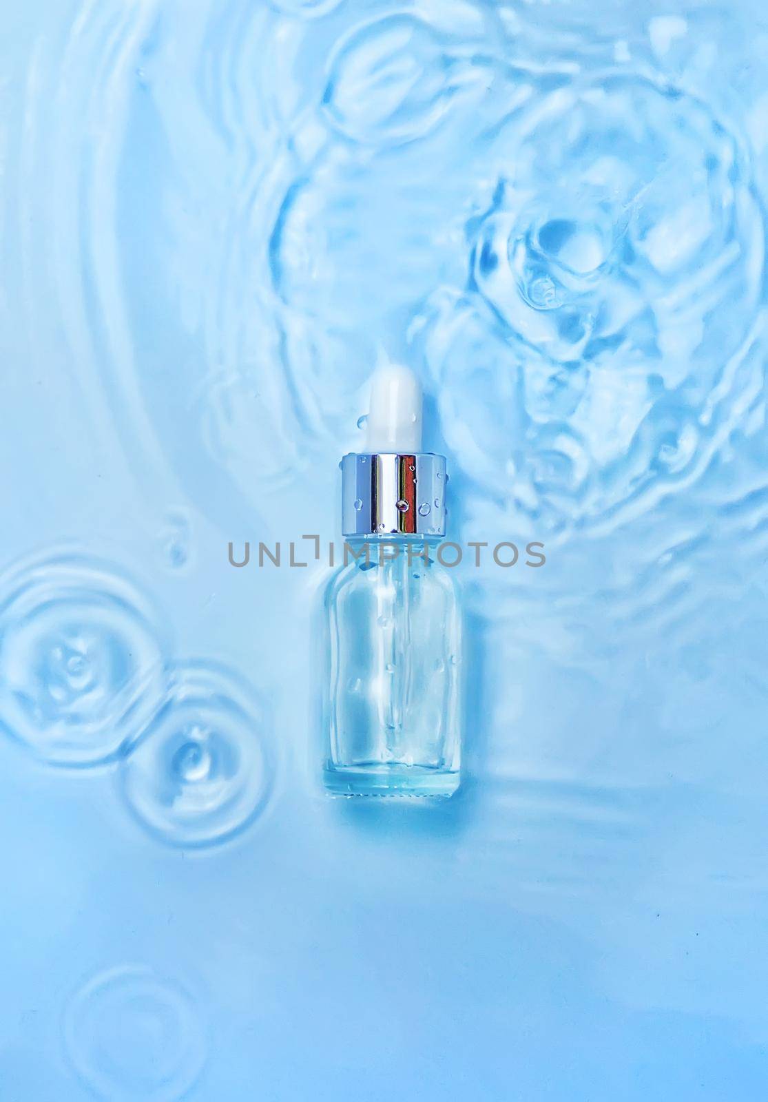 Cosmetics in a bottle in water, skin hydration concept. Hyaluronic acid. Selective focus. Nature.