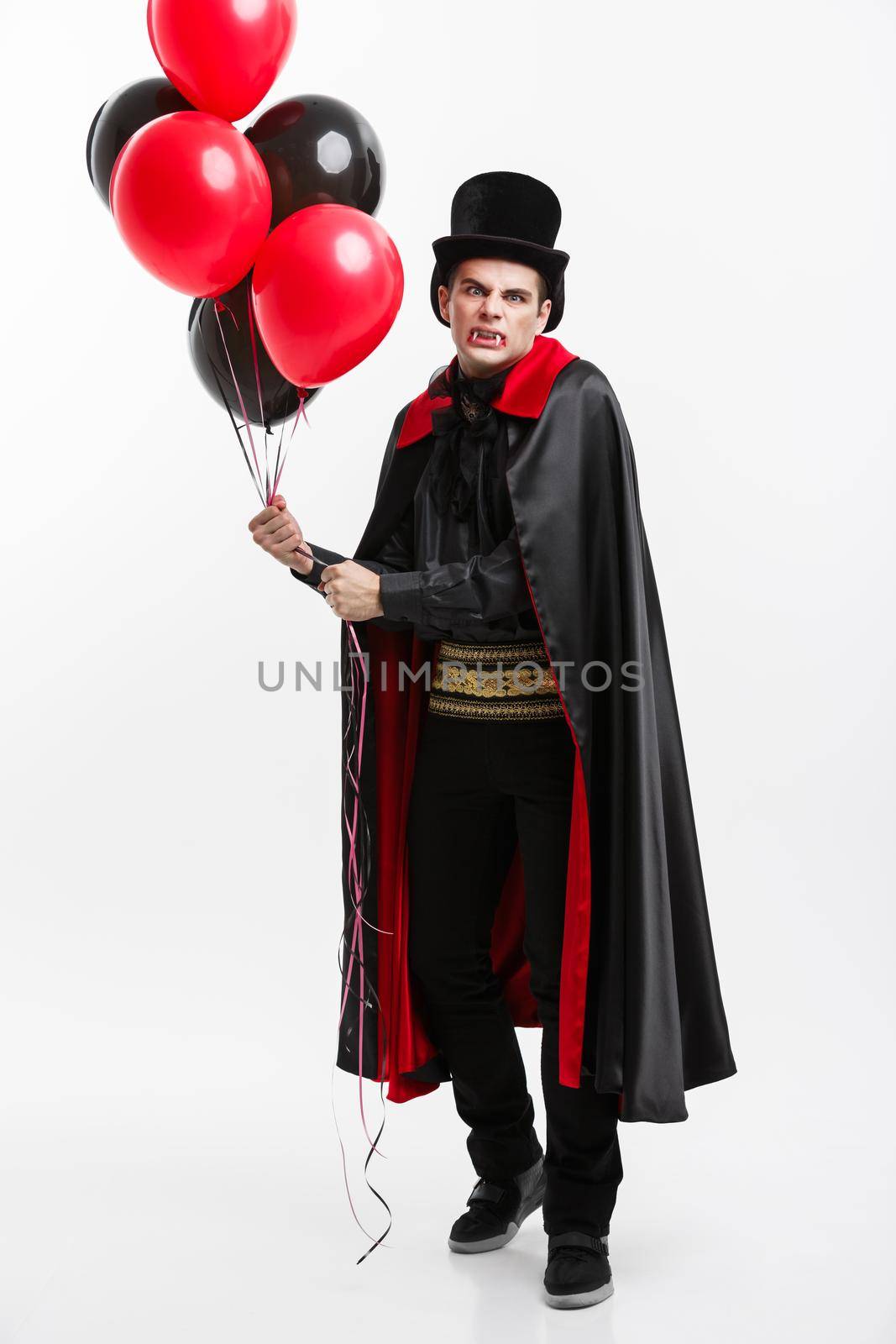 Vampire Halloween Concept - Full-lenght Portrait of handsome caucasian Vampire in black and red halloween costume.