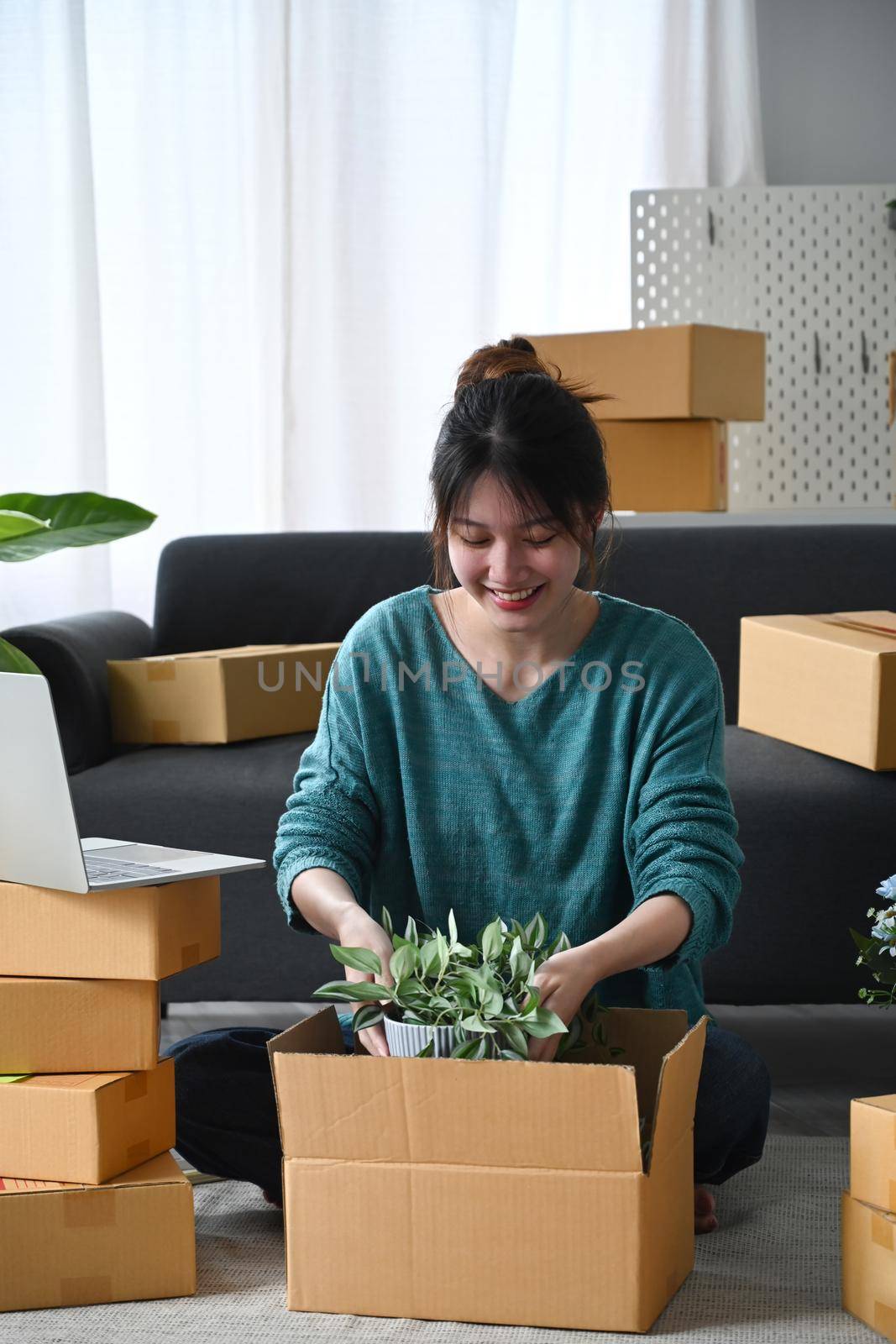 Young woman small business owner packing product in cardboard box for delivery to customers.
