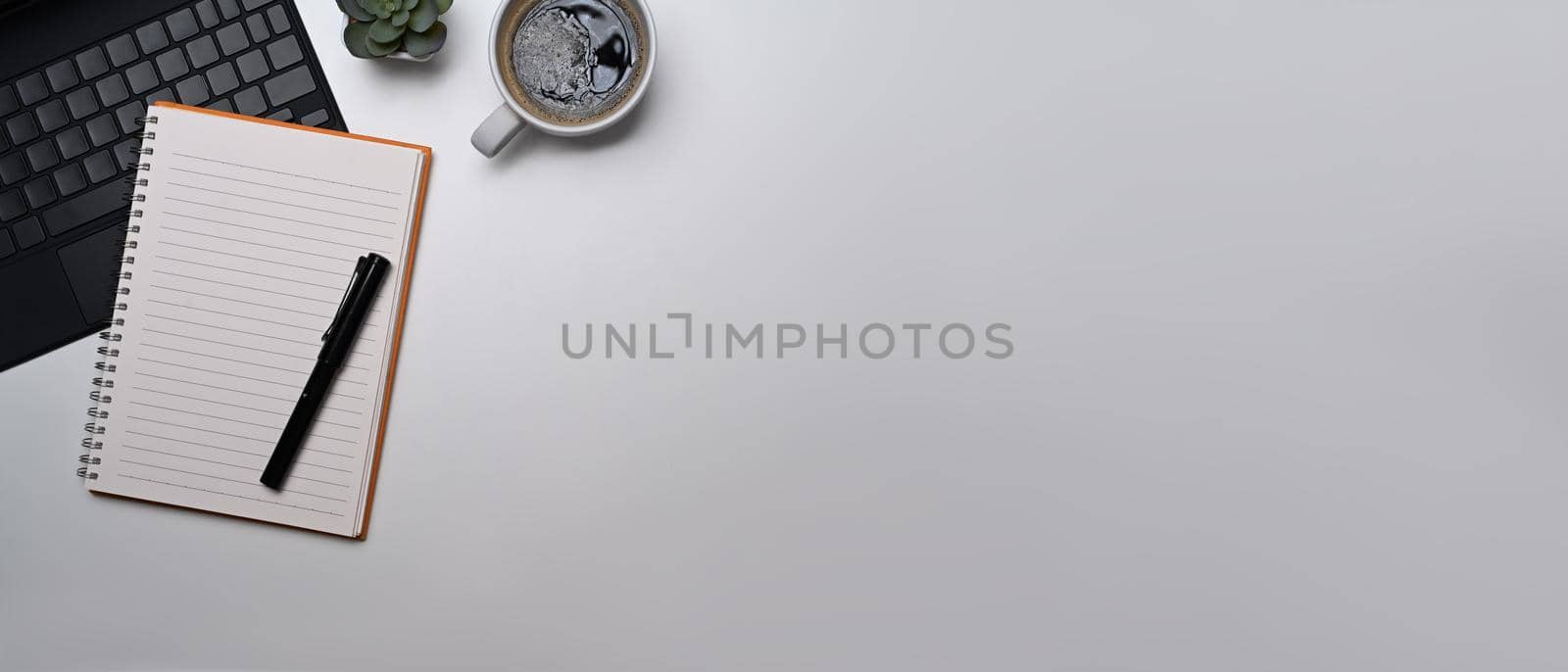 Flat lay blank notebook, laptop computer, and coffee cup on white background. Copy space for your text.