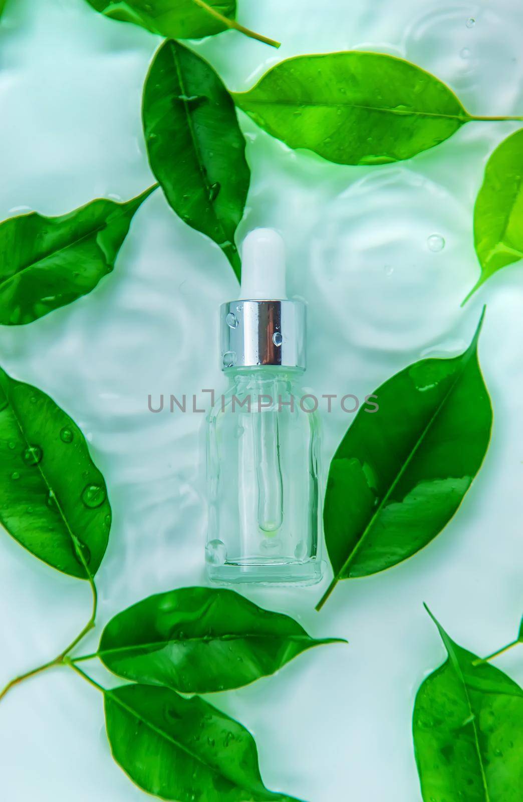 Cosmetics in a bottle in water, skin hydration concept. Selective focus. Nature.