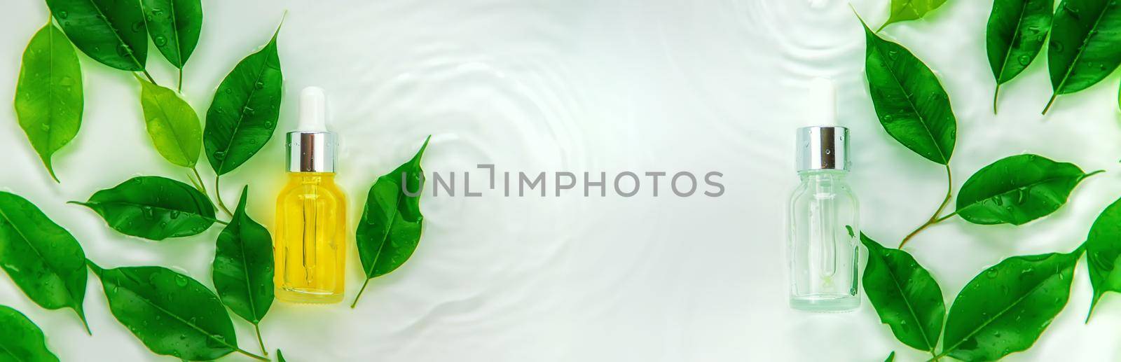 Cosmetics in a bottle in water, skin hydration concept. Selective focus. by yanadjana