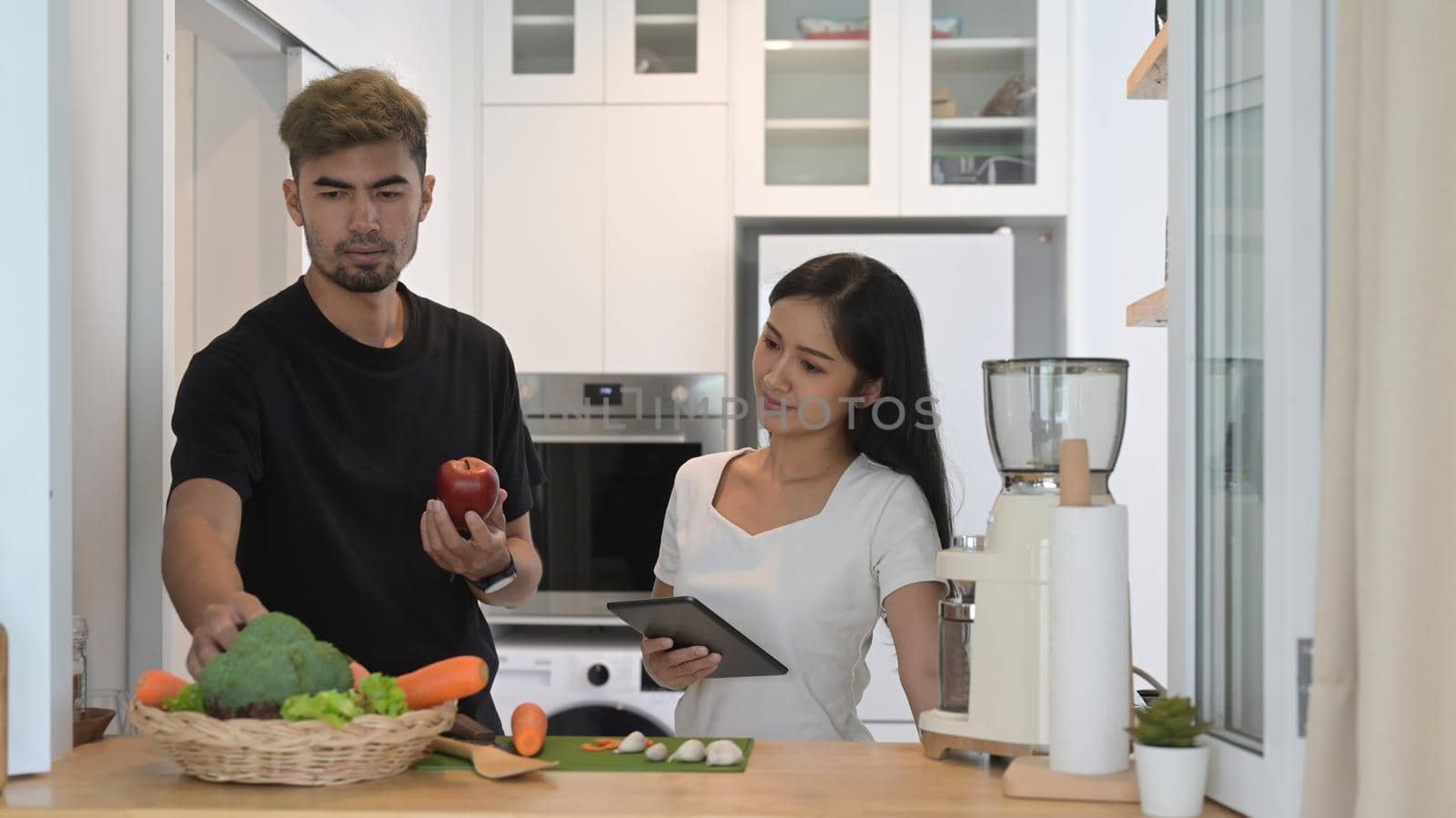 Happy young couple preparing ingredient for making vegetarian food in home kitchen.