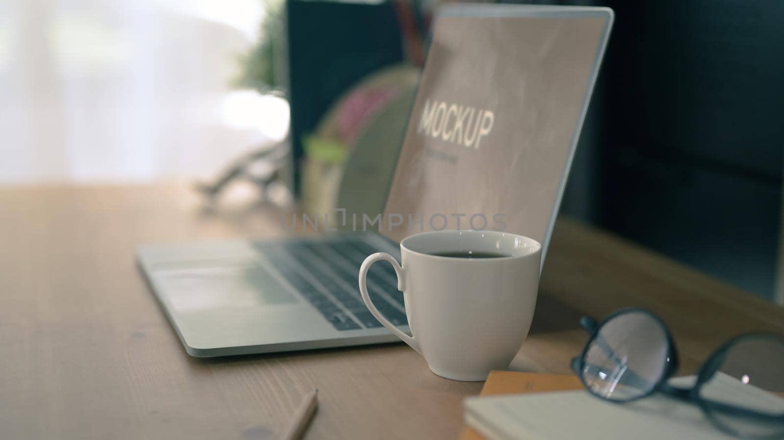 Computer laptop, coffee cup, glasses and notebook on wooden table. Comfortable workplace.
