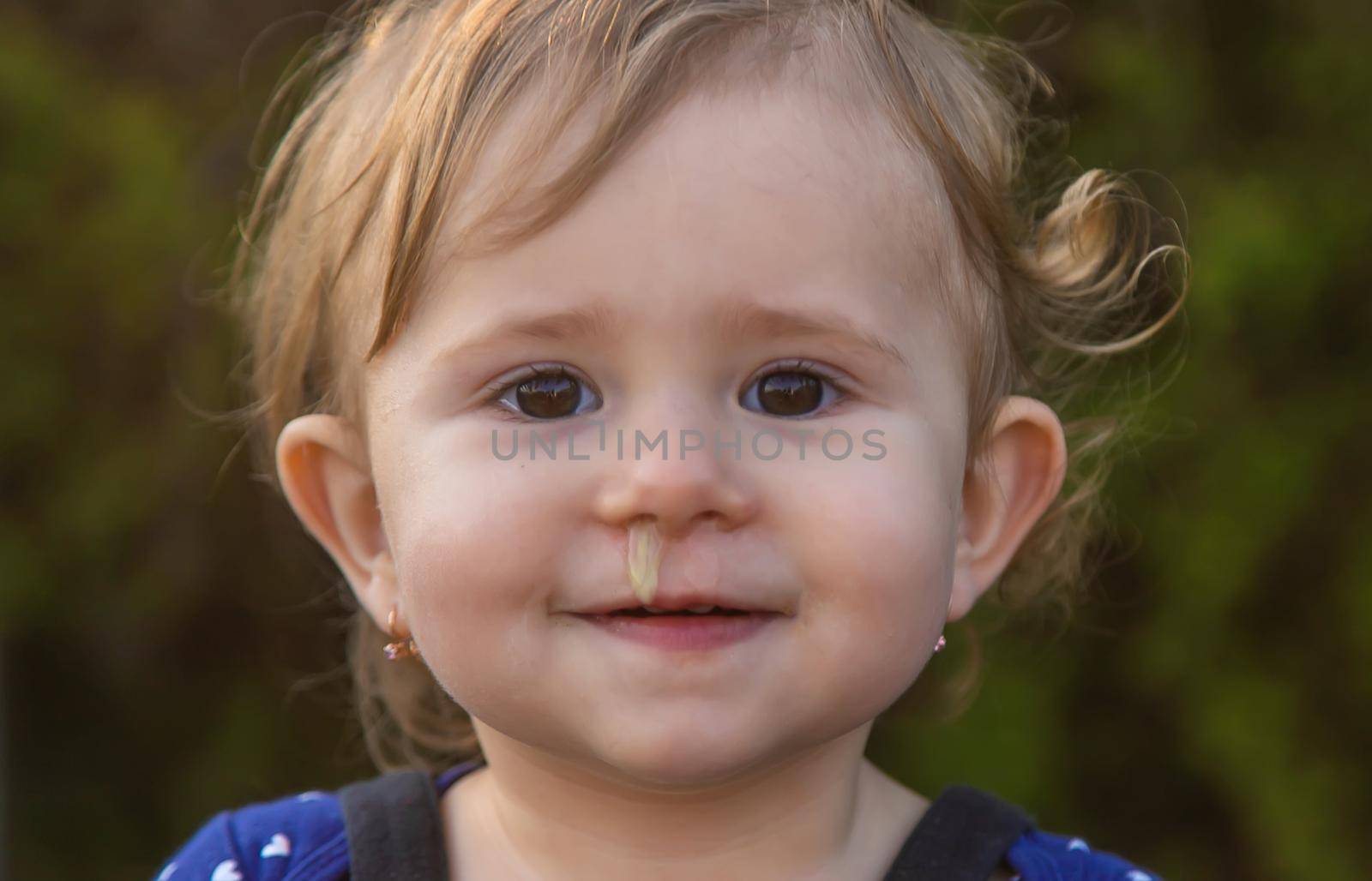 Baby plays snot in the street with a cold nose. Selective focus. Child.