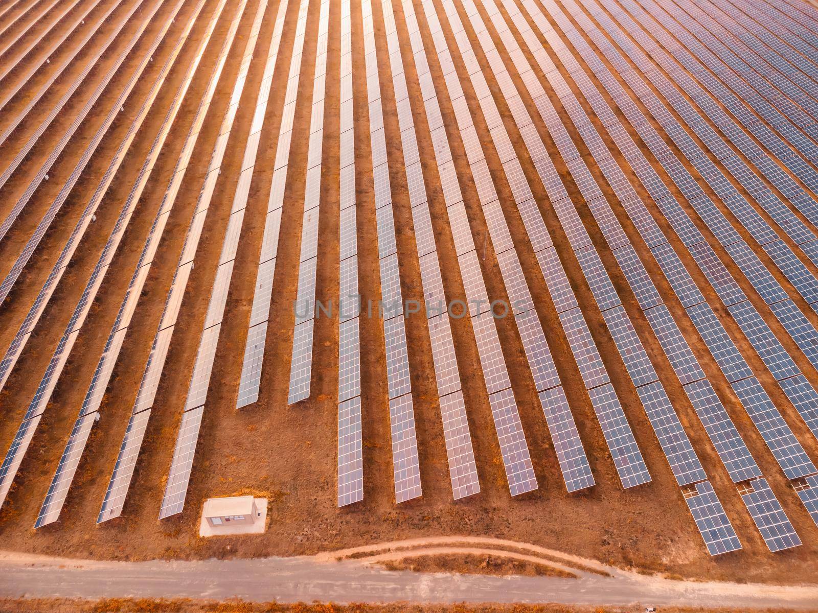 Aerial top view of a solar panels power plant. Photovoltaic solar panels at sunrise and sunset in countryside from above. Modern technology, climate care, earth saving, renewable energy concept