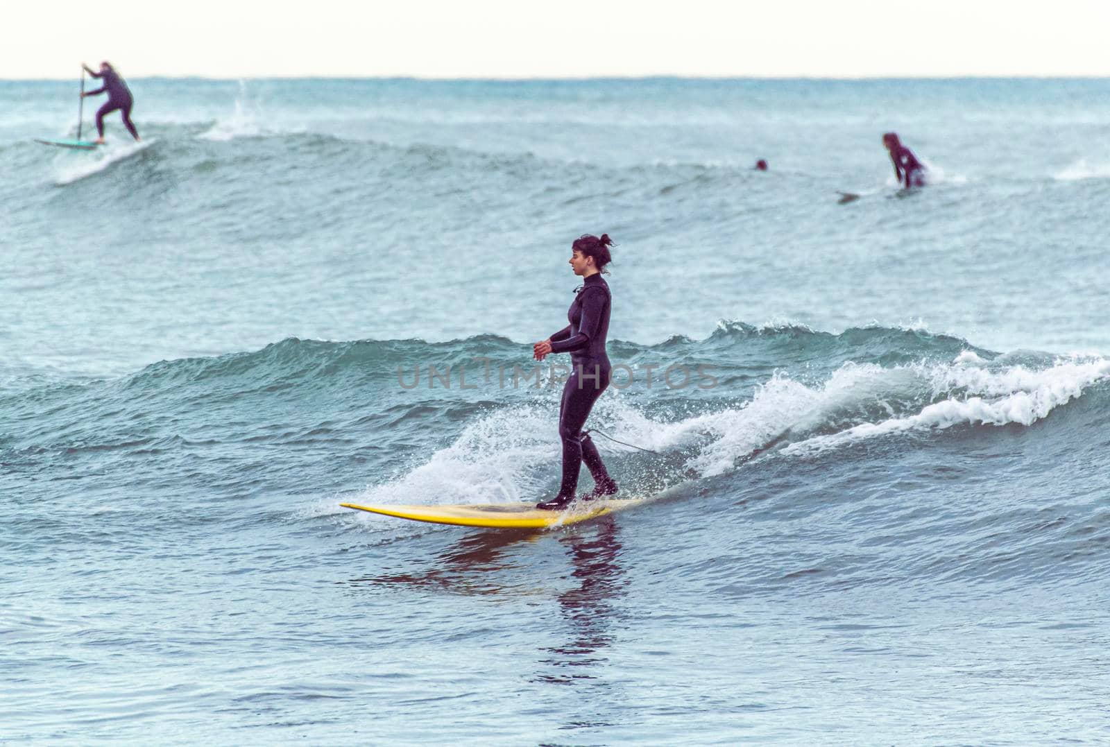 Imperia, Italy, 24/01/2021: Young girl rides the waves of the sea with the surfboard