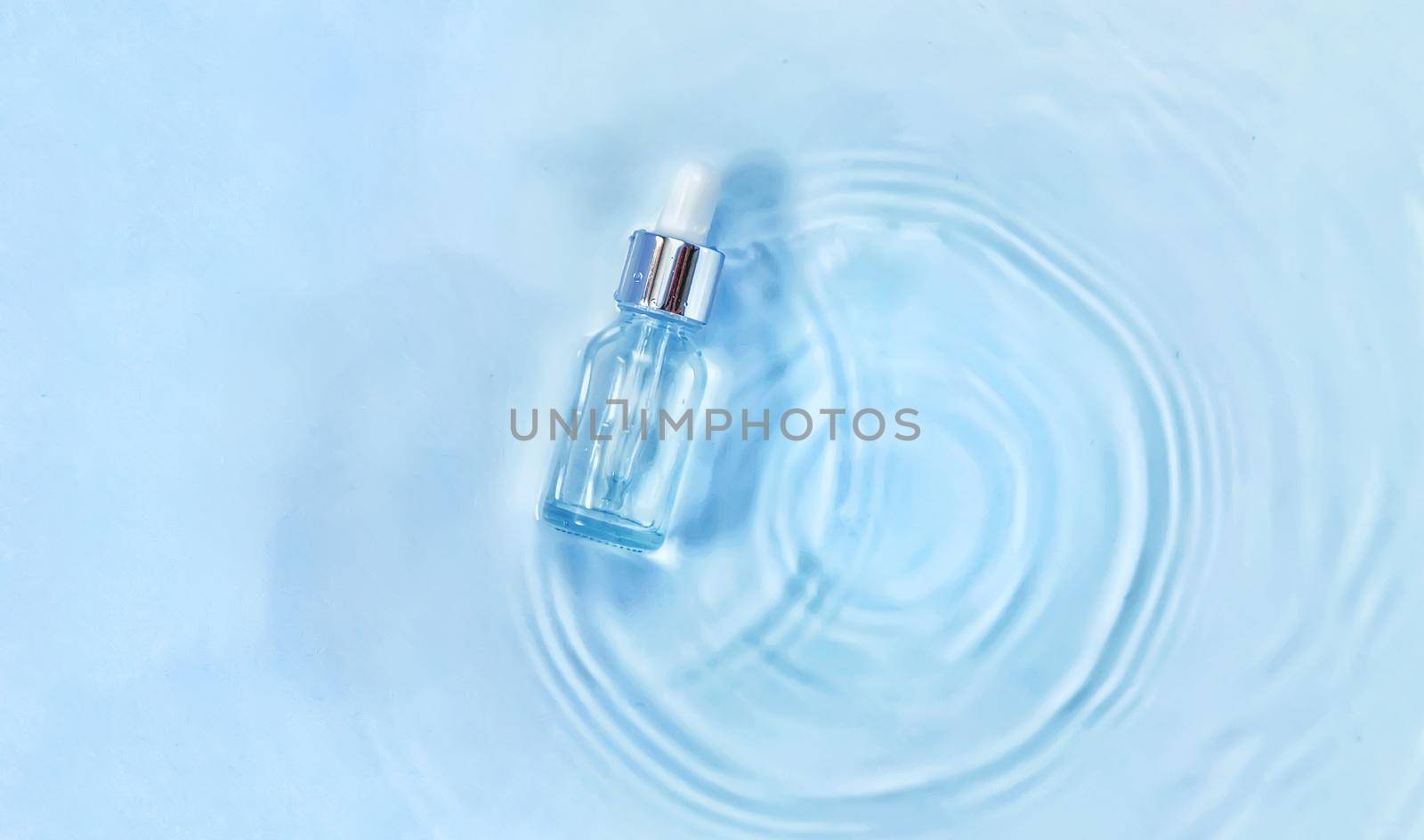Cosmetics in a bottle in water, skin hydration concept. Hyaluronic acid. Selective focus. Nature.