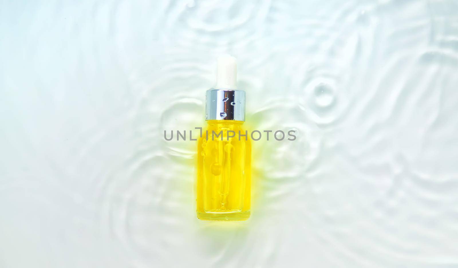 Cosmetics in a bottle in water, skin hydration concept. Hyaluronic acid. Selective focus. by yanadjana
