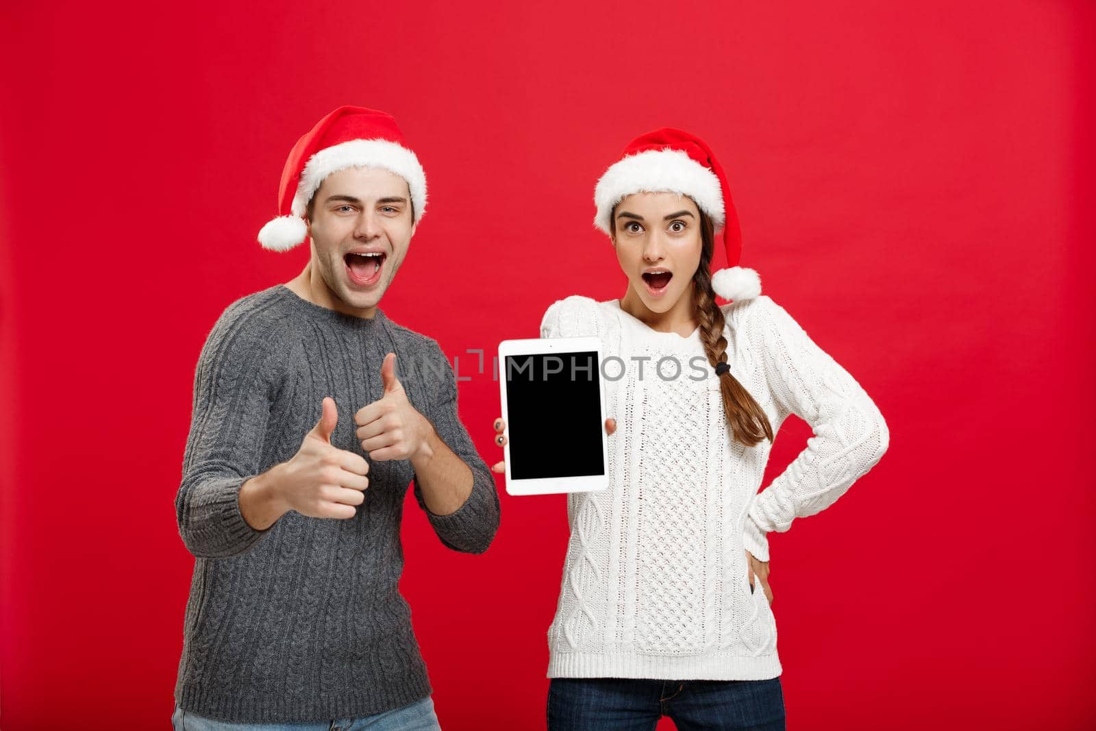 Christmas concept - Happy young couple in sweaters celebrating christmas with playing and dancing by Benzoix