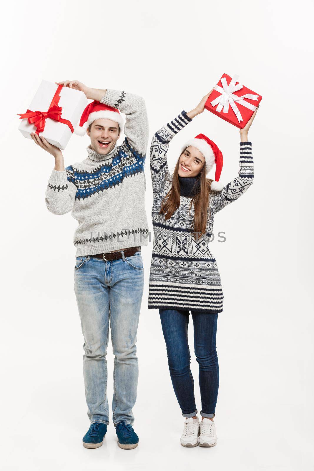 Christmas Concept - Young adorable couple holding presents isolated on white grey background
