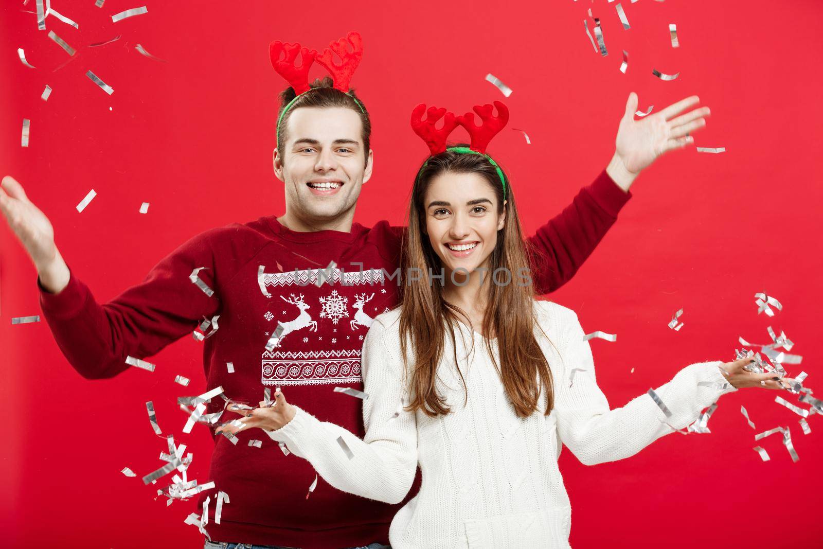 Christmas Concept - Happy caucasian man and woman in reindeer hats celebrating christmas toasting with champagne flutes, congratulating on xmas by Benzoix