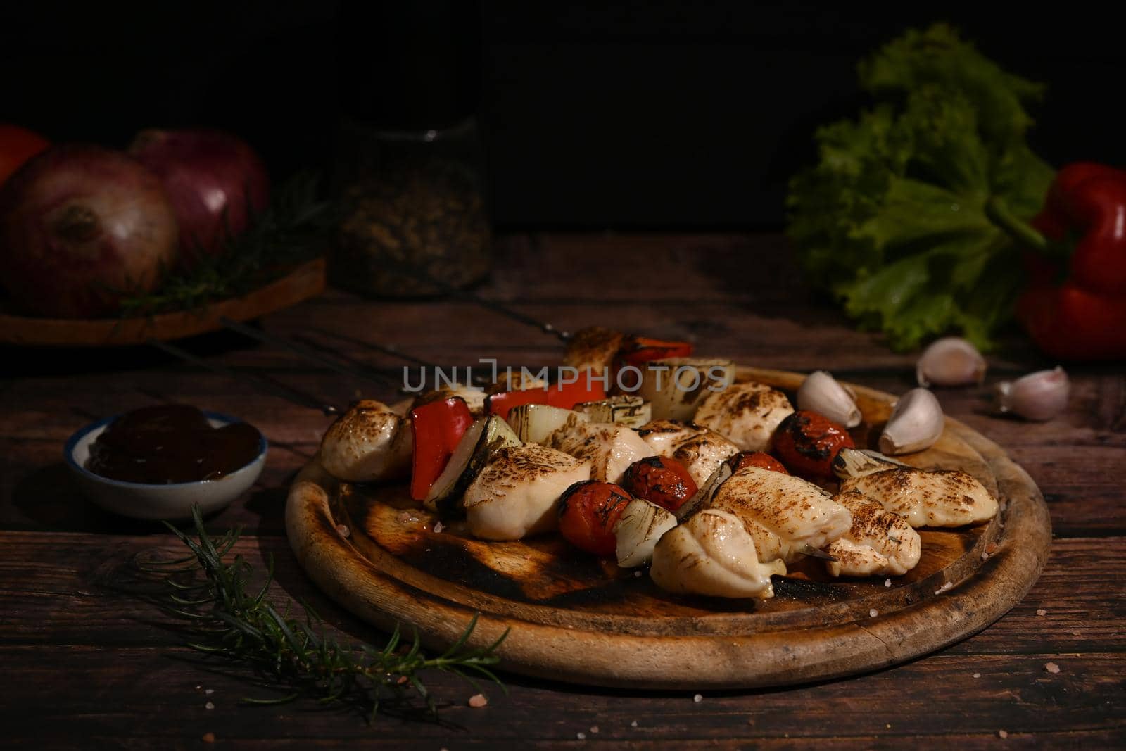 Delicious chicken shish kebab skewer barbecue with vegetables and spices and barbecue sauce on wooden cutting board.