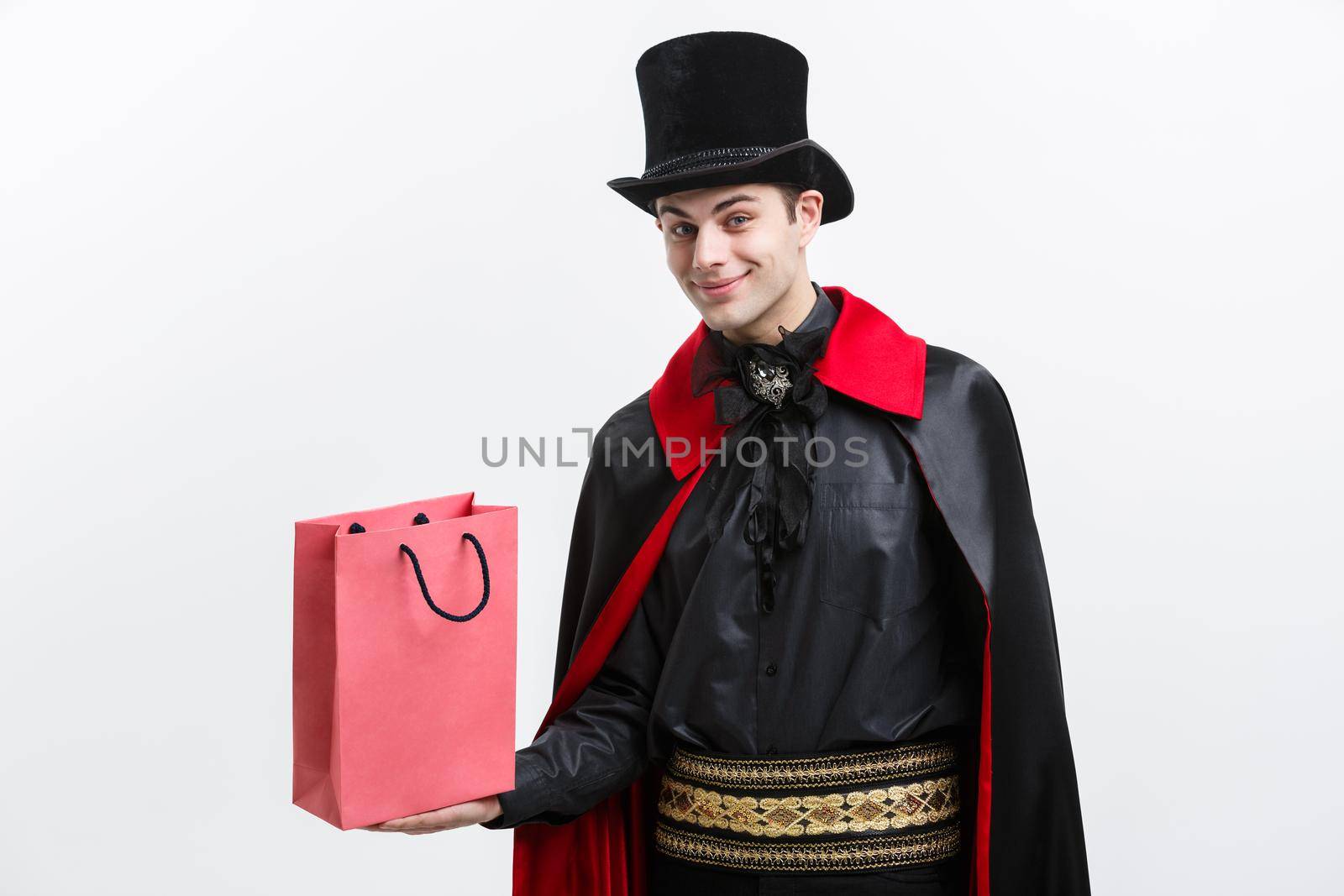 Vampire Halloween Concept - Happy handsome caucasian Vampire holding colorful shopping bag on white background