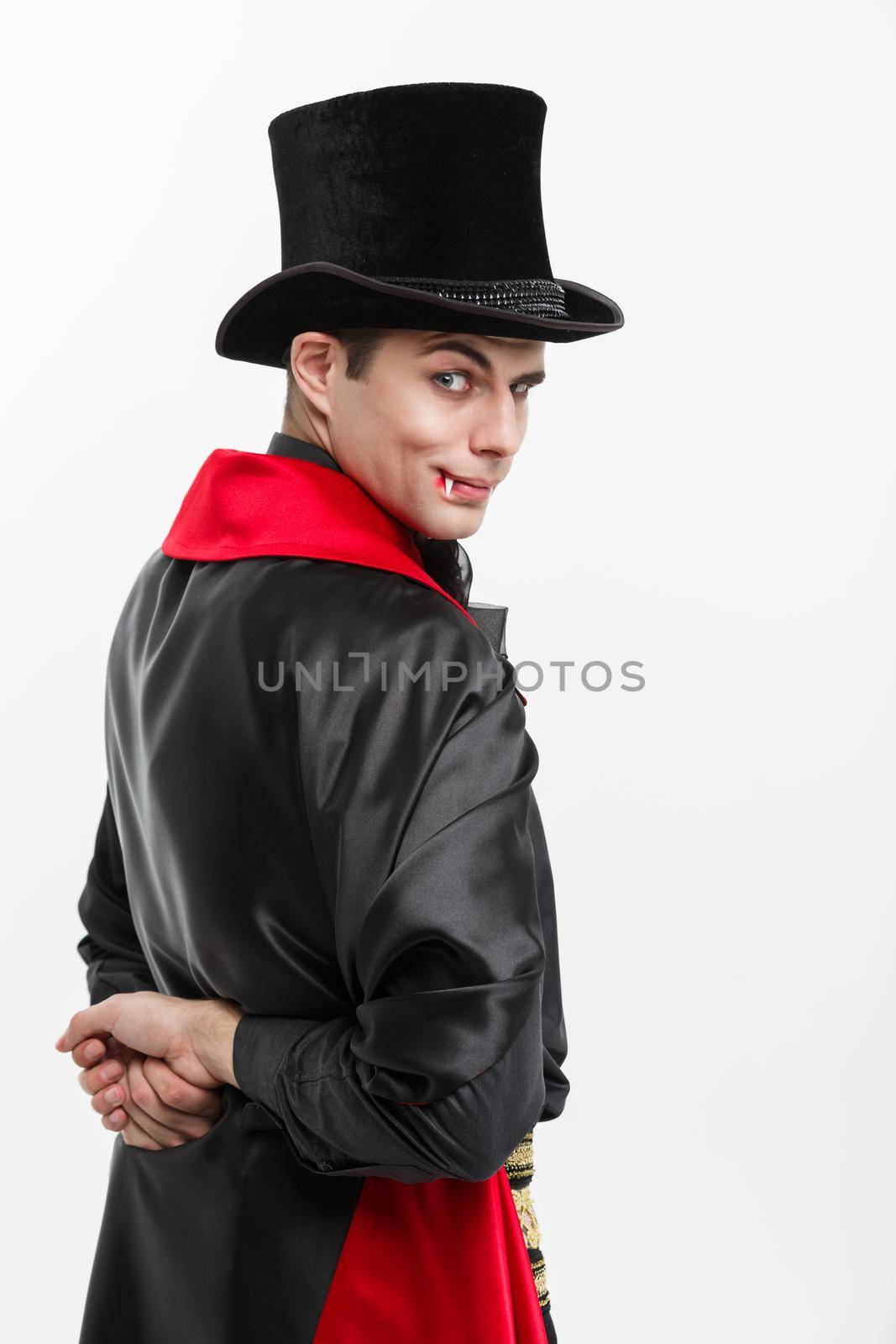 Vampire Halloween Concept - Portrait of back view handsome caucasian Vampire in black and red halloween costume isolated on white.