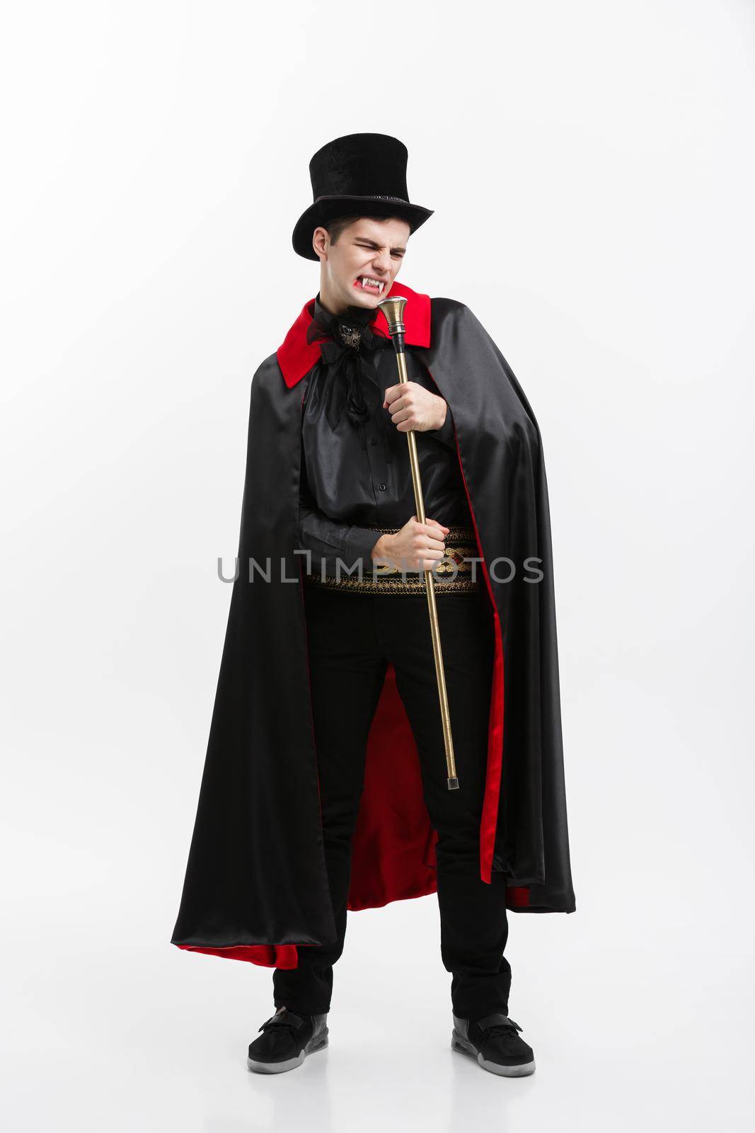 Vampire Halloween Concept - Full length Portrait of handsome caucasian Vampire in black and red halloween costume