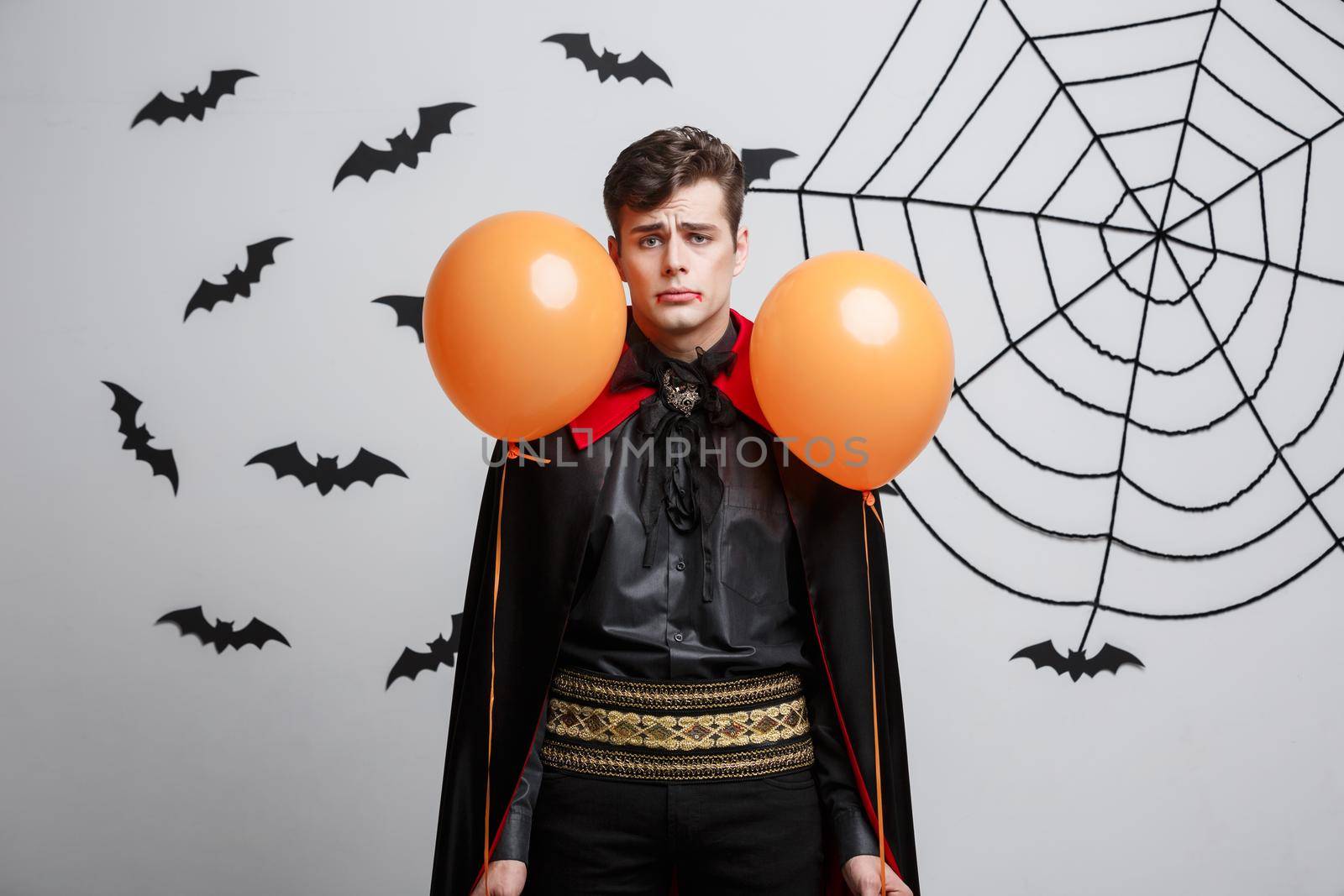 Portrait of handsome caucasian in Vampire halloween costume with colorful Balloon. by Benzoix