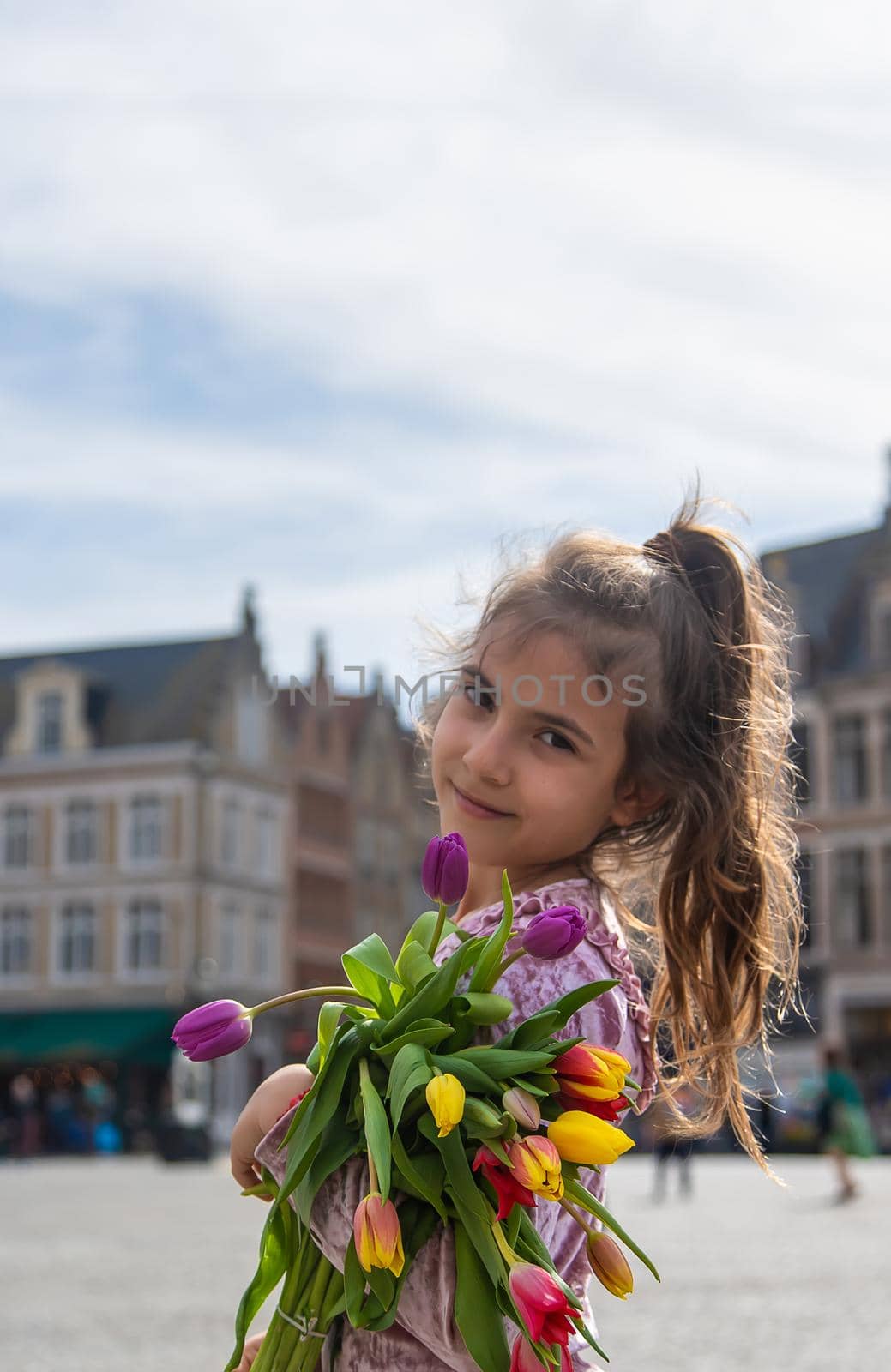 Child with a bouquet of tulips in the city. Selective focus. Kid.