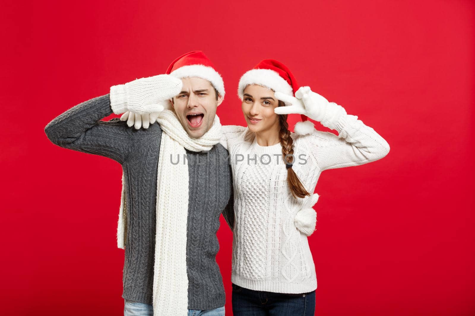 Portrait of a happy young couple posing over red studio background.